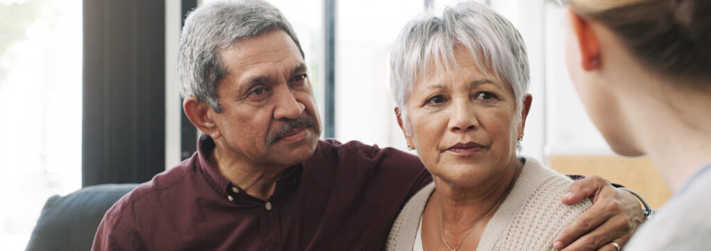 Mature Hispanic Couple listening to caregiver counselor discussing available resources.
